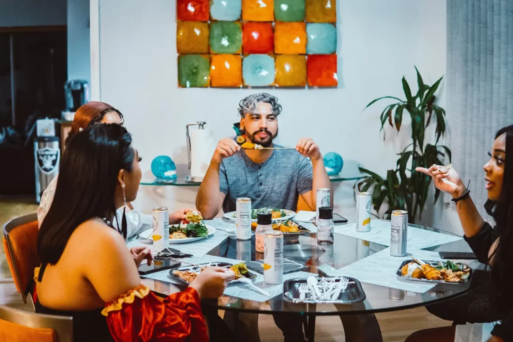 A group of adults enjoying a meal and conversation around a table at home