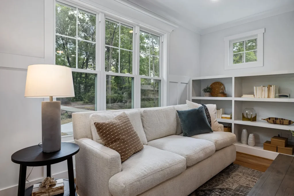A bright, comfortable living room with a sofa, lamp and large windows